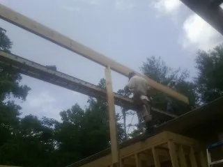 Carpenter setting a ridge beam over a new addition frame — Ice Dam Removal by Roofing Brothers in Left Hand