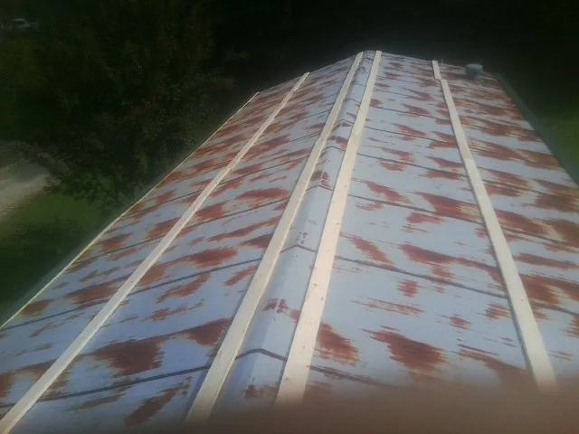 Rusted metal roof panels with new wood purlins before replacement in Left Hand