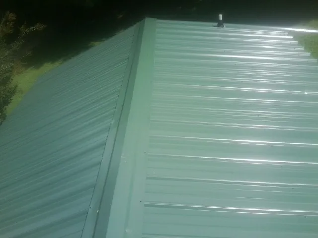 New green metal panels meeting at the ridge of a roof — Flat Roof Repair work by our crew in Left Hand