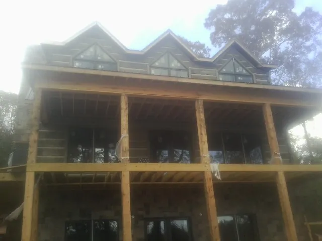 Dormers and porch framing on a large log home under construction — Roof Coating work by our crew in Left Hand