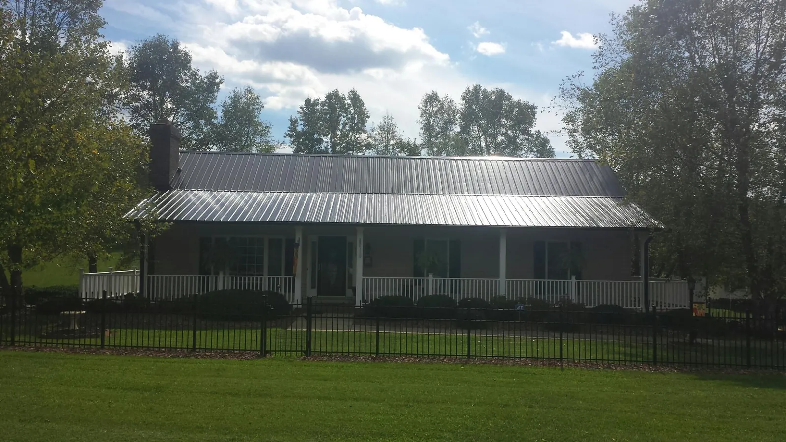 Gray metal roof on a brick ranch with a full width front porch — Gutter Guard Installation work by our crew in Left Hand